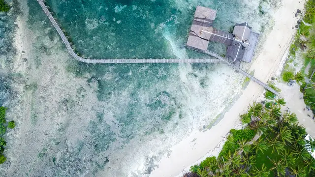 Aerial view of the wooden Cloud 9 boardwalk and viewing tower stretching over the reef at General Luna, Siargao.