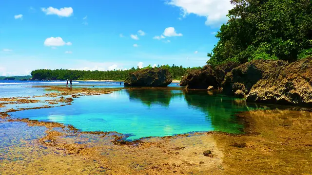 Turquoise natural tide pool framed by rock formations and jungle at Magpupungko, Pilar, Siargao.