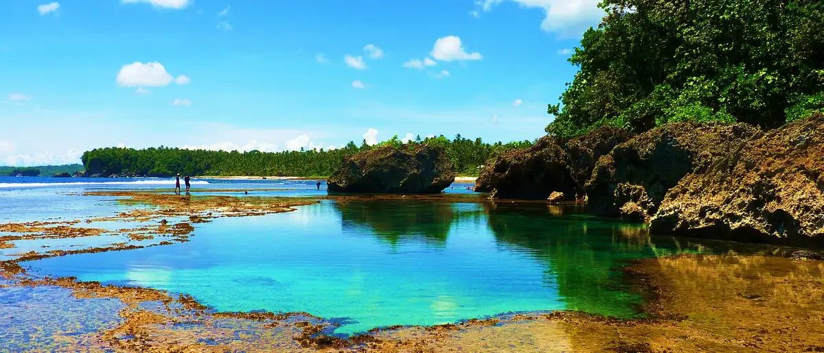 Turquoise natural tide pool framed by rock formations and jungle at Magpupungko, Pilar, Siargao.
