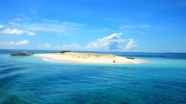 The bare white sandbar of Naked Island surrounded by turquoise sea under a blue sky, off General Luna, Siargao.