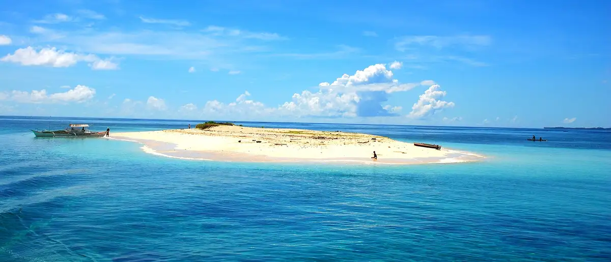 The bare white sandbar of Naked Island surrounded by turquoise sea under a blue sky, off General Luna, Siargao.
